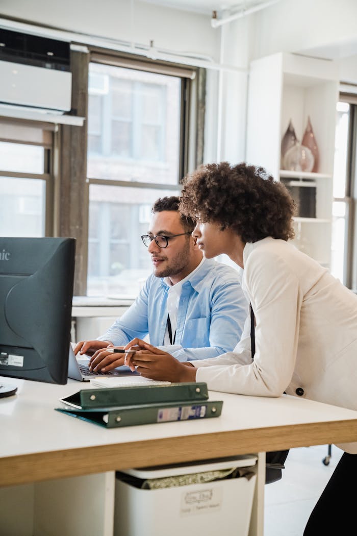 Two professionals collaborating at a desk in a modern office environment.