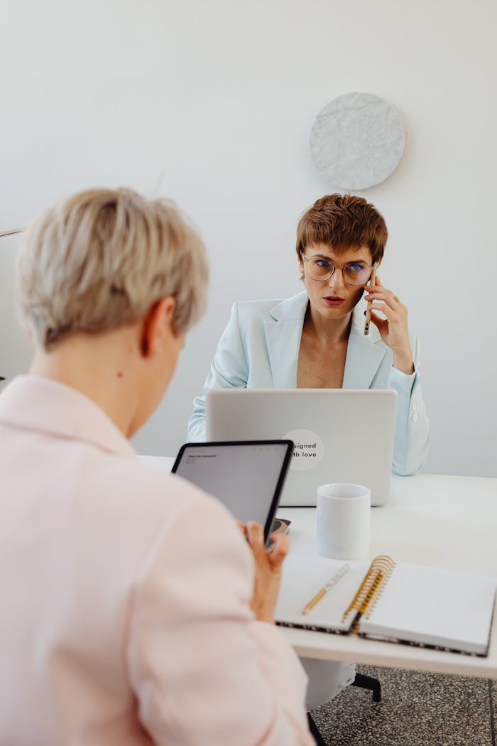 Two business professionals in an office setting engaged in work and communication.